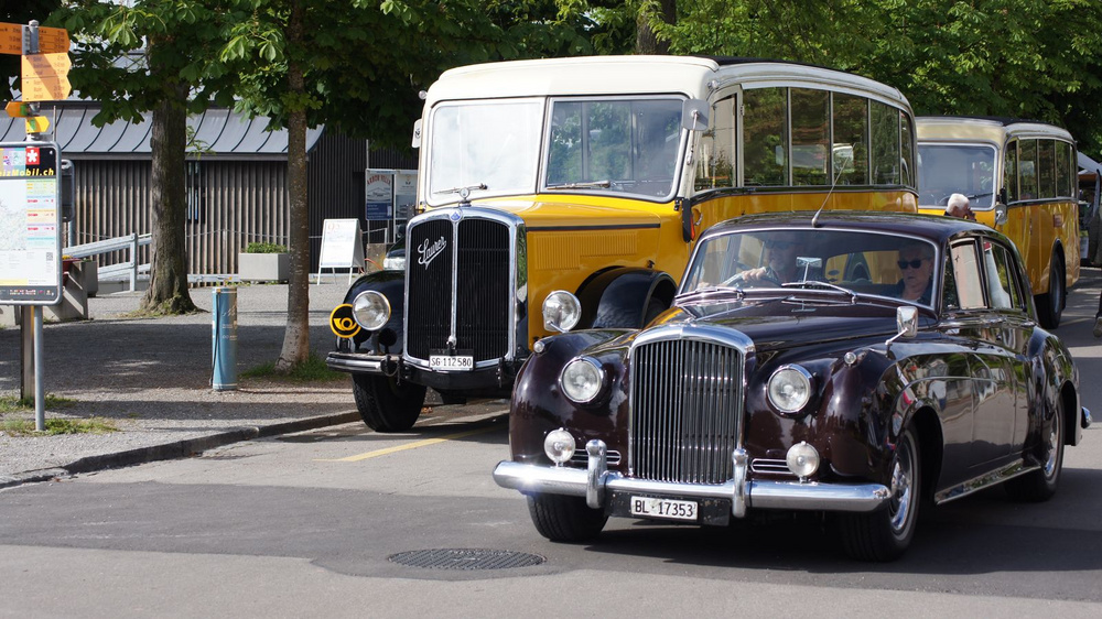Alter PostAuto Bus und antikes Auto.