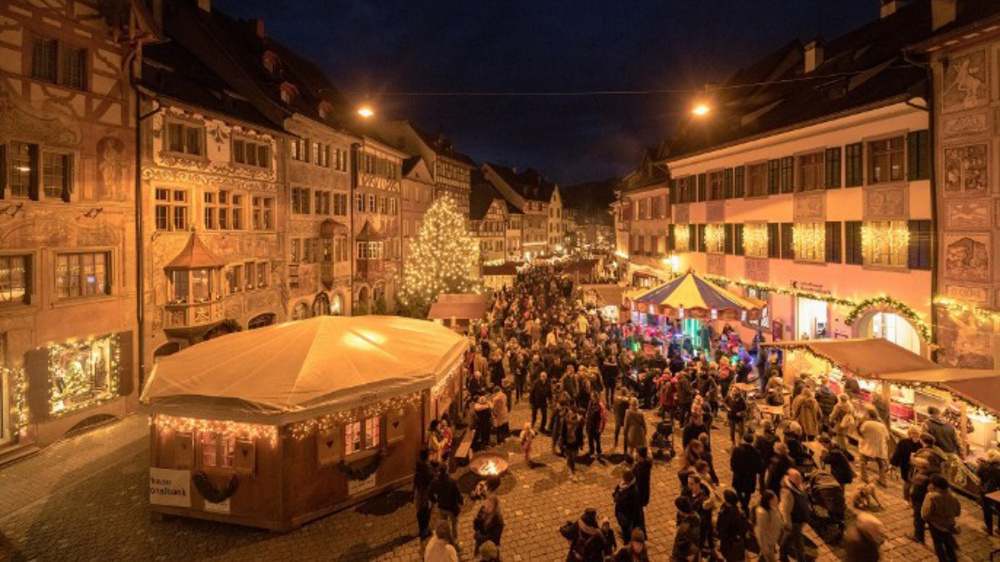Weihnachtsmarkt beleuchtet mit Menschen an Ständen