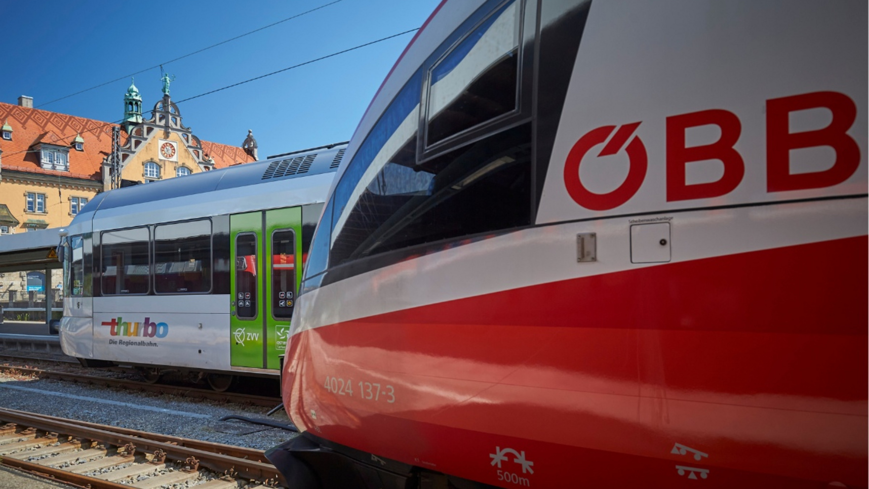 Ein Zug der ÖBB und einer von Thurbo stehen versetzt in einem Bahnhof.