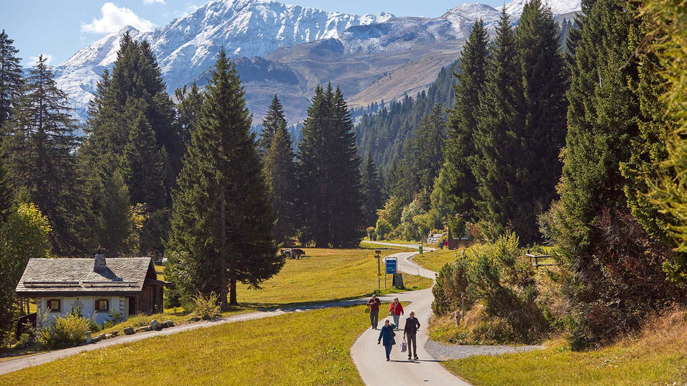 Menschen auf einem Fussweg in der herbstlichen Berglandschaft.