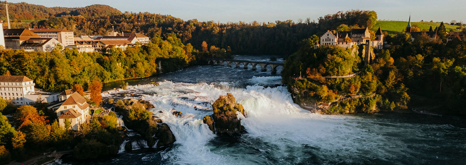Herbstliches Bild an einem Wasserfall und farbigem Wald.