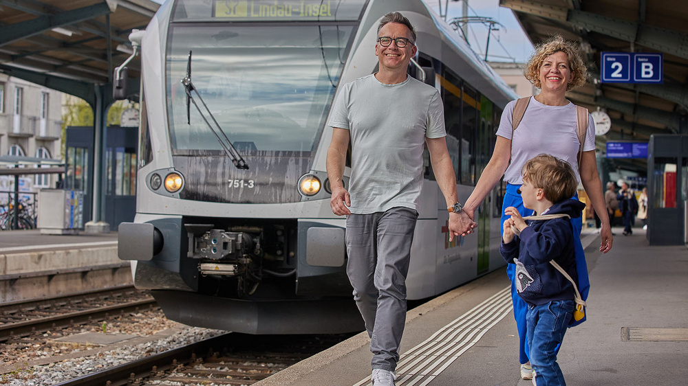 Familie vor einem Thurbo Zug an einem Bahnhof.
