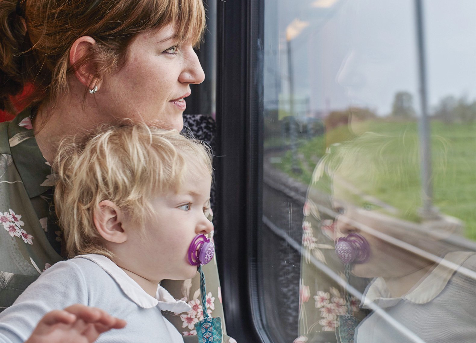 Eine Mutter schaut mit ihrem Kind aus dem Fenster eines Zugabteils.