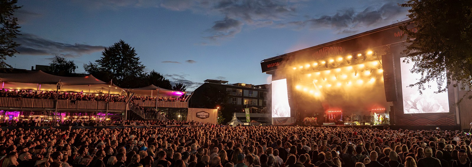 Menschenmenge vor einer beleuchtenden Bühne an einem Konzert.